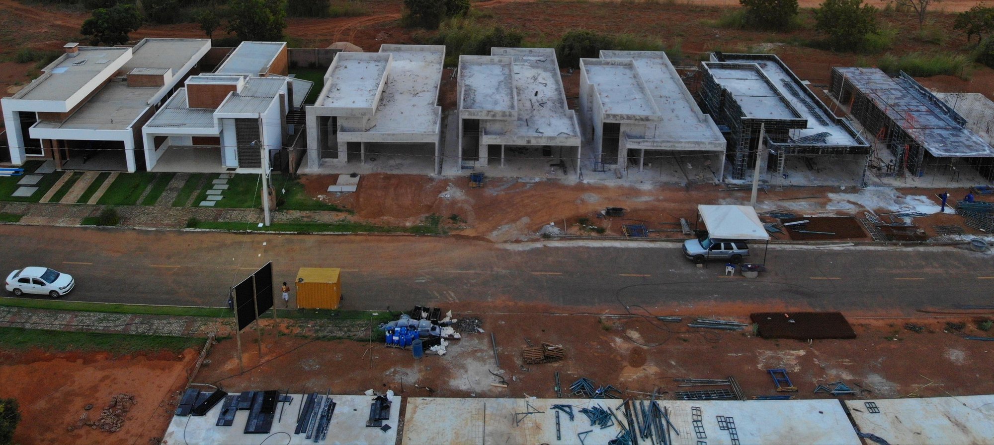 A rua do Setor das Mansões vista de cima: à esquerda a casa acabada, com jardim; à direita, na mesma rua, a fileira de casas em concreto nu, ainda sem acabamento, com a obra em andamento